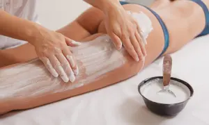 Mani esperte applicano fanghi drenanti su gambe e glutei, un trattamento che promette di aiutare a dimagrire e rimodellare il corpo.