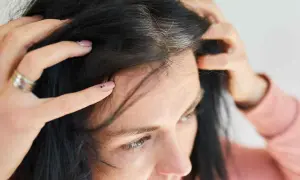 Mani che toccano i primi capelli bianchi tra i capelli scuri, un segno del tempo che passa.
