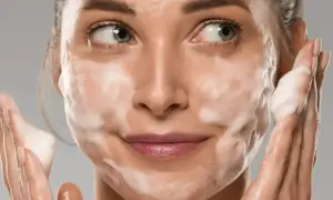 Donna con schiuma sul viso, che mostra come si usa il detergente viso per una pulizia profonda e delicata.