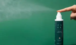 Un dito preme il vaporizzatore di un tonico viso idratante, un gesto che rinfresca e rivitalizza la pelle.