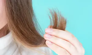 Mani che accarezzano capelli secchi, mostrando la necessità di burro di karitè sui capelli asciutti o bagnati per nutrirli.