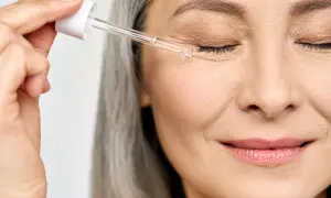 Donna applica un siero contorno occhi, un gesto quotidiano per capire la differenza tra collagene e acido ialuronico.