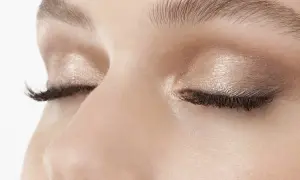 Occhi chiusi con trucco luminoso, ciglia lunghe e folte. Uno sguardo spento che riflette un momento di quiete interiore.