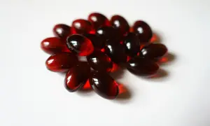 Un mucchio di capsule rosse traslucide, forse integratori di fosfatidil colina, su sfondo bianco.