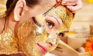 Una donna riceve un trattamento di bellezza con una maschera viso oro, scoprendo i suoi benefici rigeneranti.
