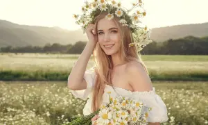 Ragazza con corona di margherite e bouquet, capelli biondi luminosi come dopo shampoo alla camomilla effetti naturali.