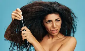 Donna con capelli crespi prova a usare una piastra, sperando in un trattamento anti crespo efficace.