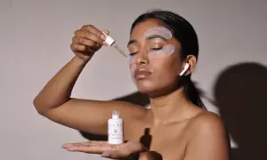 Una donna applica un siero con un contagocce, con patch occhi per un trattamento rivitalizzante. Scopri a cosa servono i patch occhi per una pelle luminosa.