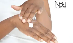 Mani che si applicano crema, per una pelle morbida e liscia. Il logo NB Cosmetics in primo piano.