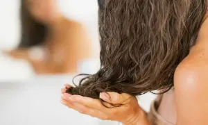 Mani che accarezzano capelli lunghi e bagnati, pronti per dormire con i capelli bagnati e svegliarsi con onde naturali.