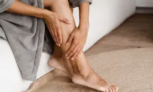 Mani che accarezzano una gamba, un gesto che suggerisce come avere gambe lisce e curate, avvolte in un morbido accappatoio.