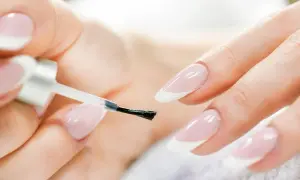 Mani perfette con la manicure a casa. Smalto trasparente applicato con cura su unghie con french manicure.