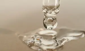 Goccia di siero con retinolo, che riflette la luce come il sole. La sua consistenza trasparente e le bollicine catturano l'essenza della cura della pelle.