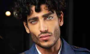 Uomo con capelli mossi scuri e occhi azzurri penetranti, un look che ispira su come farsi i capelli mossi uomo.