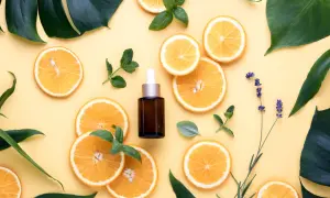 Siero viso con niacinamide e vitamina c, circondato da fette d'arancia, foglie verdi e lavanda.