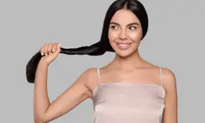 Una donna sorride mentre tiene una ciocca dei suoi lunghi capelli neri. Sembra che si chieda: "henne cos'è?