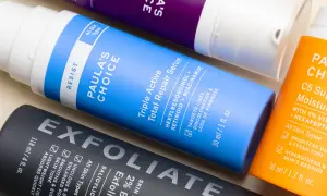 Flaconi di prodotti per la cura della pelle, tra cui un siero con retinolo e vitamina c, per una routine anti-età completa.