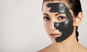 Donna con maschera al carbone sul viso, per scoprire i benefici di una pelle purificata e luminosa.