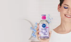 Donna sorridente rimuove il trucco con acqua micellare Nivea, mostrando come si usa acqua micellare per una pulizia delicata.