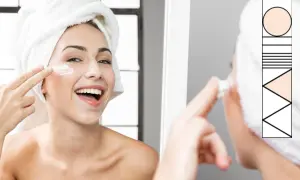 Donna sorridente con turbante, applica crema viso. Un rituale di bellezza per un perfetto ordine skincare.