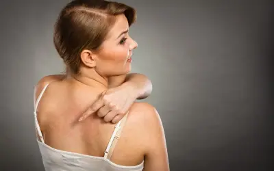 Donna si tocca la schiena arrossata, indicando un fastidioso punto nero che non esce.