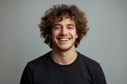 Uomo sorridente con splendidi capelli ricci uomo, un look naturale e vivace.