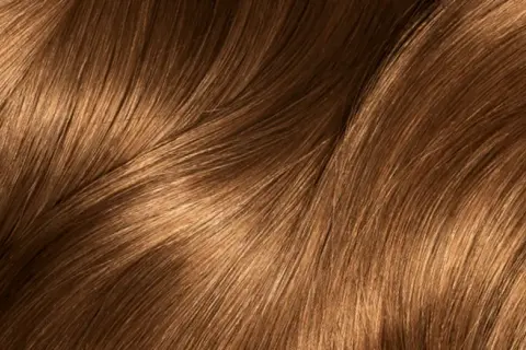 Capelli castani con riflessi dorati che ricordano i colpi di sole caramello, mossi e luminosi.