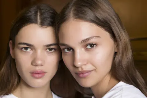 Close-up of two young women with brown hair and natural makeup.