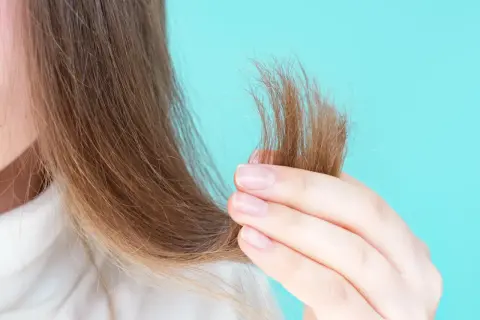 Mani che accarezzano capelli secchi, mostrando la necessità di burro di karitè sui capelli asciutti o bagnati per nutrirli.