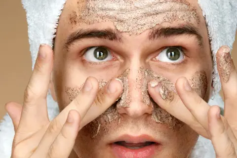 Uomo con scrub viso, pronto per la cura della pelle. Cosa mettere dopo lo scrub viso per un risultato ottimale.