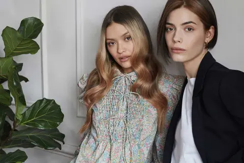 Due modelle con capelli biondi e castani, una con abito floreale, l'altra con blazer. L'armocromia inverno capelli valorizza i loro toni.