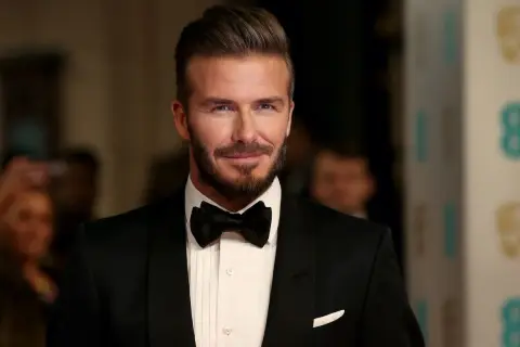 Uomo con impeccabili capelli all'indietro, barba curata e smoking nero con papillon.