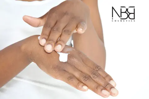 Mani che si applicano crema, per una pelle morbida e liscia. Il logo NB Cosmetics in primo piano.