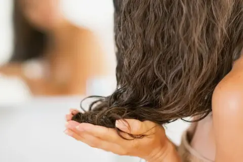 Mani che accarezzano capelli lunghi e bagnati, pronti per dormire con i capelli bagnati e svegliarsi con onde naturali.
