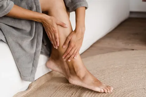 Mani che accarezzano una gamba, un gesto che suggerisce come avere gambe lisce e curate, avvolte in un morbido accappatoio.