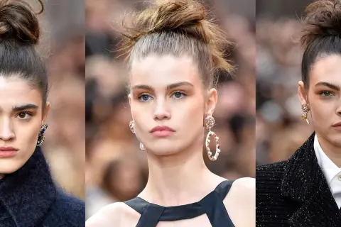 Tre modelle con un elegante chignon capelli, orecchini vistosi e makeup naturale.