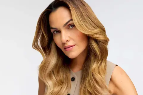 Donna con capelli biondo miele, effetto colpi di sole fai da te, che incorniciano il viso con onde morbide.
