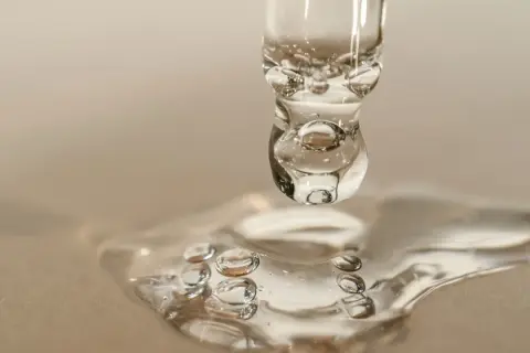 Goccia di siero con retinolo, che riflette la luce come il sole. La sua consistenza trasparente e le bollicine catturano l'essenza della cura della pelle.