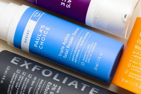 Flaconi di prodotti per la cura della pelle, tra cui un siero con retinolo e vitamina c, per una routine anti-età completa.