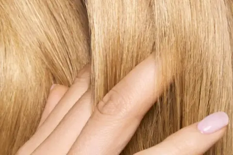 Dita accarezzano capelli biondi e setosi. Posso usare la maschera per capelli prima dello shampoo per ottenere questa morbidezza.