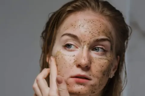 Ragazza con scrub sul viso, un gesto di cura per capire quante volte fare lo scrub viso per una pelle luminosa.