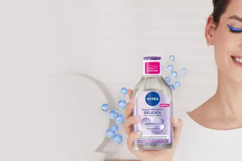 Donna sorridente rimuove il trucco con acqua micellare Nivea, mostrando come si usa acqua micellare per una pulizia delicata.
