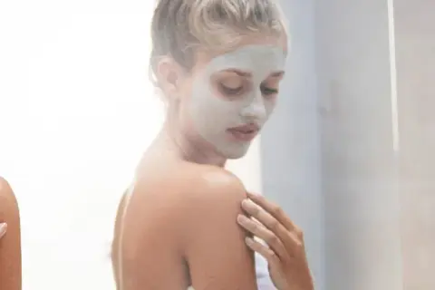 Donna con maschera viso, un rituale di bellezza prima o dopo la doccia per una pelle radiosa.
