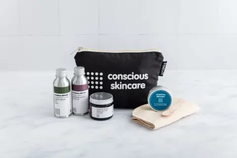 Kit skincare viso con borsa nera, flaconi, crema e maschera.