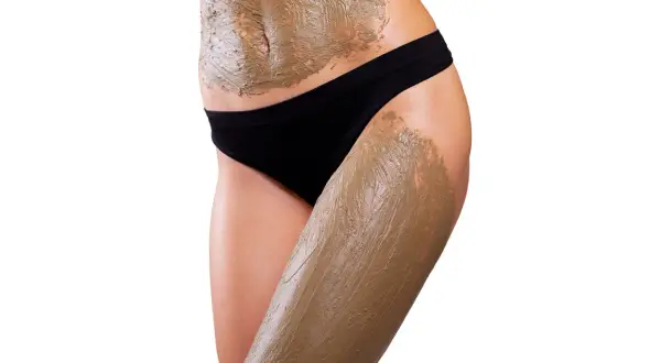 Corpo femminile con fanghi anticellulite applicati su addome e coscia. Quante volte a settimana per risultati ottimali?