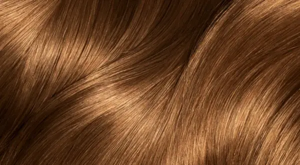Capelli castani con riflessi dorati che ricordano i colpi di sole caramello, mossi e luminosi.