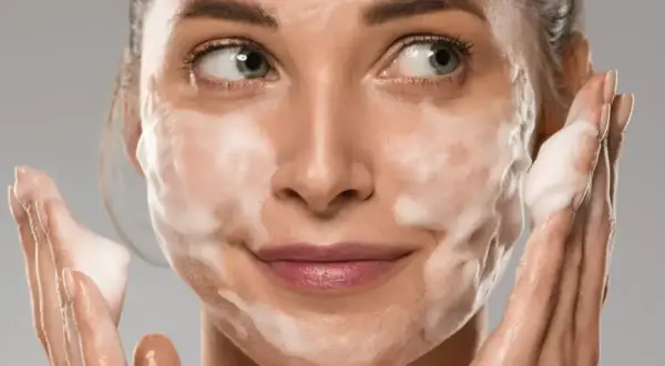 Donna con schiuma sul viso, che mostra come si usa il detergente viso per una pulizia profonda e delicata.