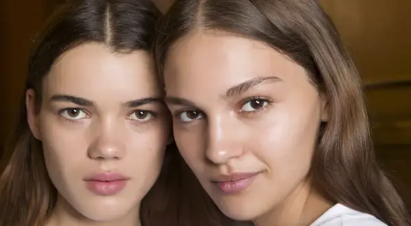 Close-up of two young women with brown hair and natural makeup.