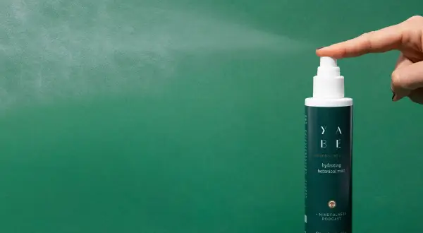 Un dito preme il vaporizzatore di un tonico viso idratante, un gesto che rinfresca e rivitalizza la pelle.