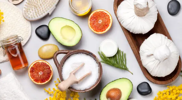 Ingredienti per uno scrub fatto in casa: sale, avocado, arancia, miele, lavanda e una spazzola per il corpo.
